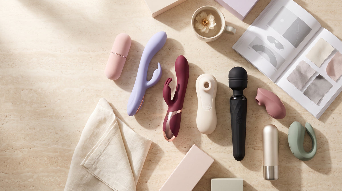 Lubrifiant Durex, stimulateur Satisfyer, vibromasseur rabbit et plug en verre alignés sur fond violet